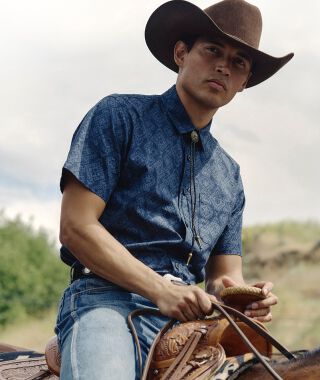 Man riding a horse wearing a Pendleton shirt