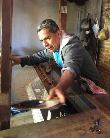 Image of craftsman weaving rug