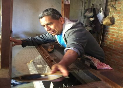 Oaxacan Weaver standing at a rug loom.