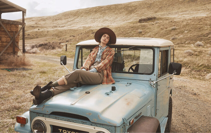 Woman sitting on a car outside wearing a Pendleton wool shirt