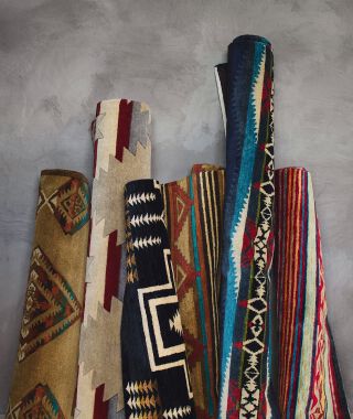 Colorful Pendleton Rugs rolled up leaning against a walll