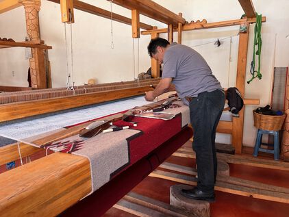 Oaxacan Weaver standing at a rug loom.