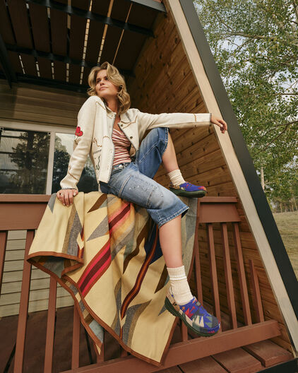 Woman sitting on a porch wearing Crocs x Pendleton clogs