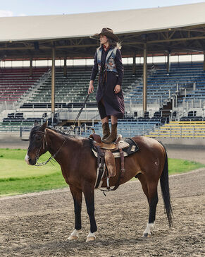 Woman rodeo rider standing on her horse wearing a Pendleton vest