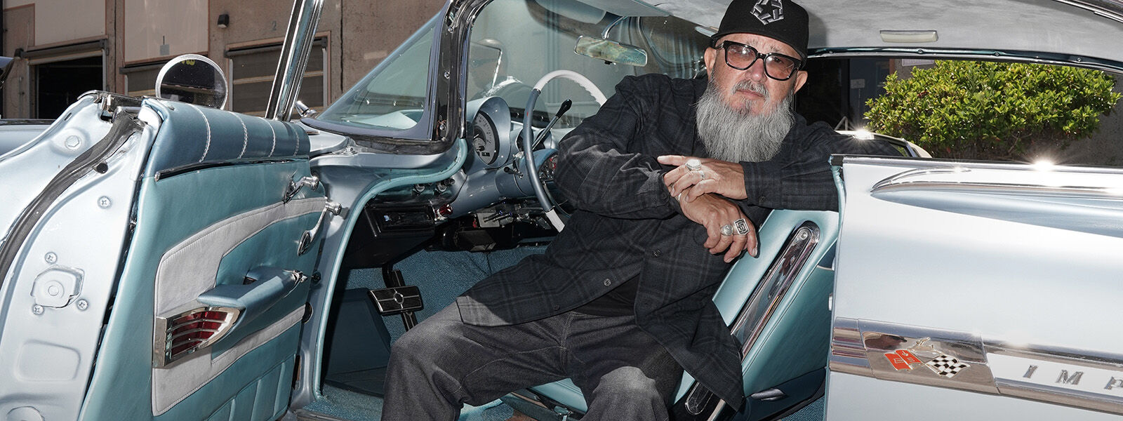 Artist Bobby Ruiz sittng in his 1959 Chevy Impala
