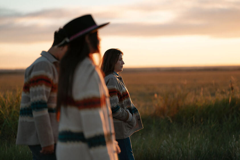 Group standing outside watchin the sunset wearing Addie Roanhorse jackets and sweaters