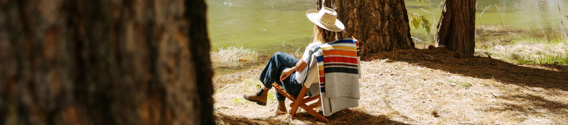 Woman sitting at a lake in Yosemite with a Pendleton Yosemite Blanket