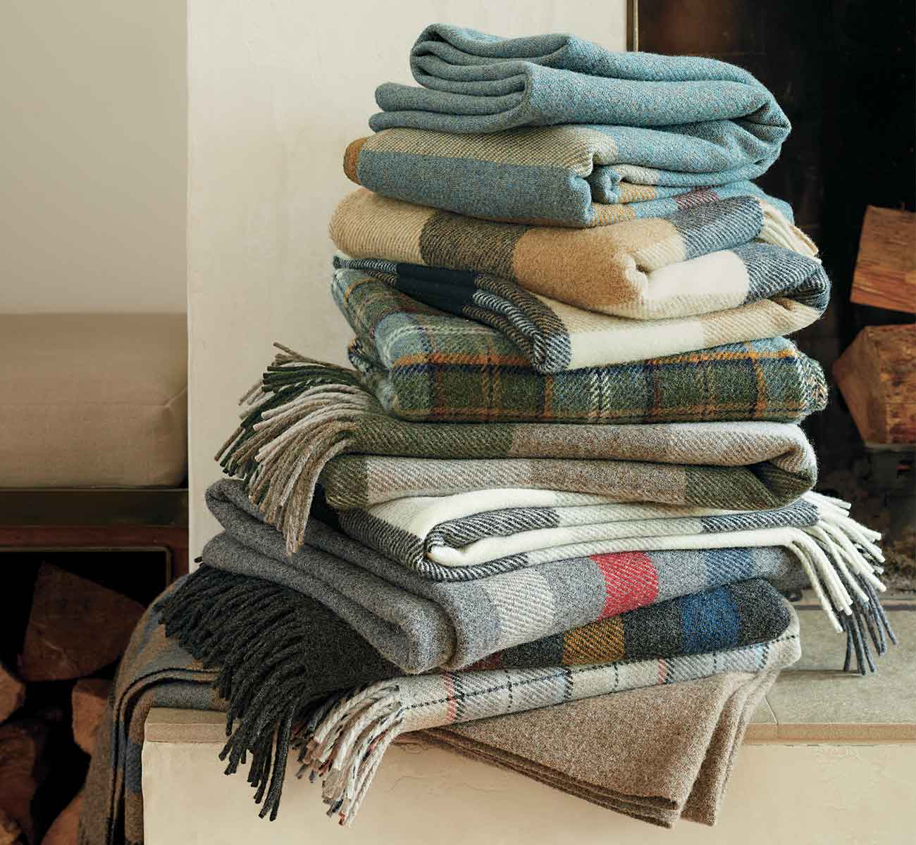 Stack of plaid blankets sitting on a fire hearth